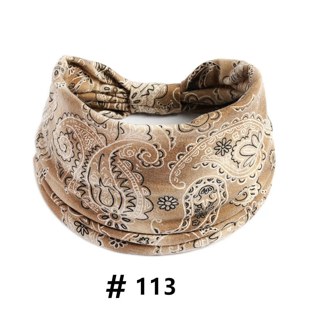 A beige cotton headband with an intricate paisley print worn around the head.