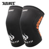 A pair of black athletic knee sleeves with orange text showing strength and power