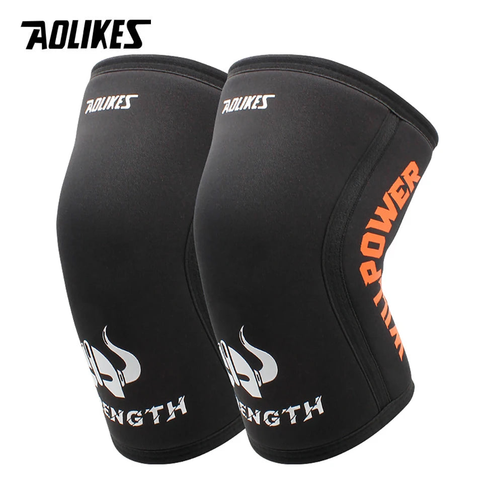 A pair of black athletic knee sleeves with orange text showing strength and power