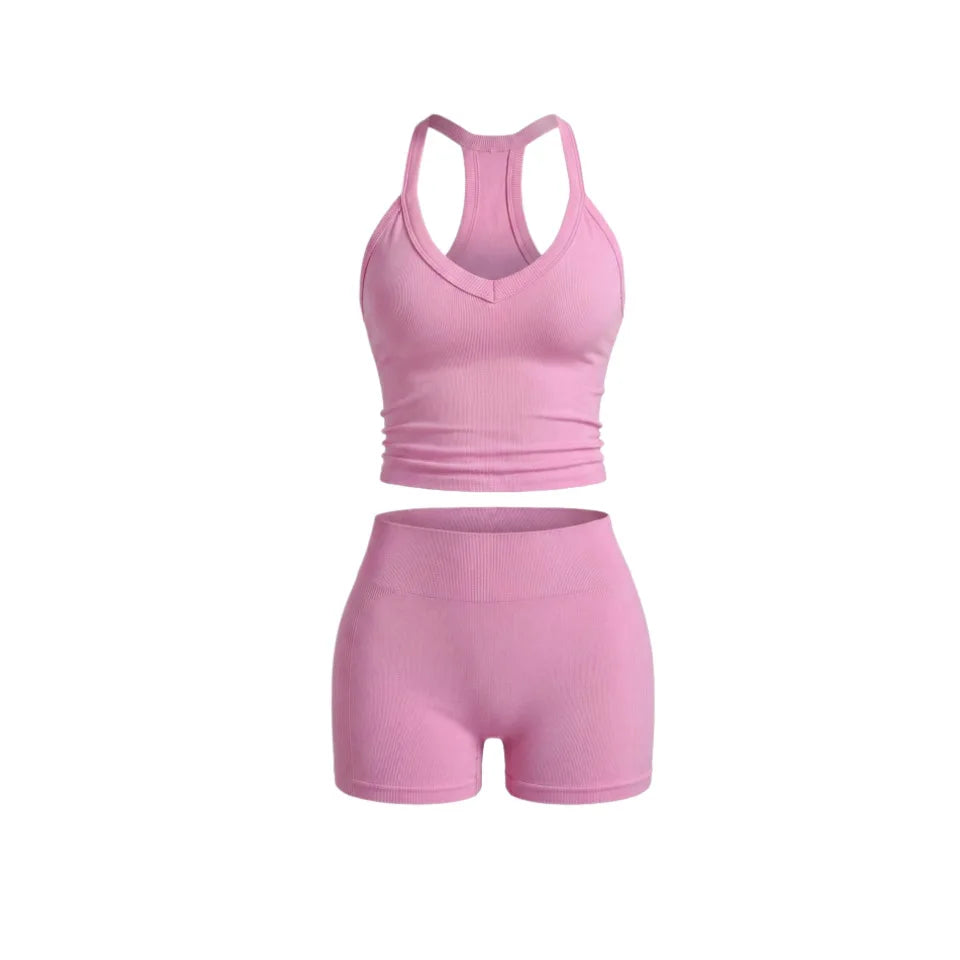 A pink two-piece women's yoga set featuring a racerback tank top and matching shorts.