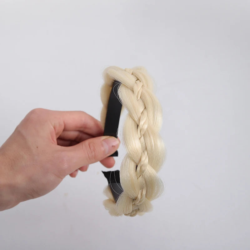 A hand is holding a light blonde twisted braided wig headband.