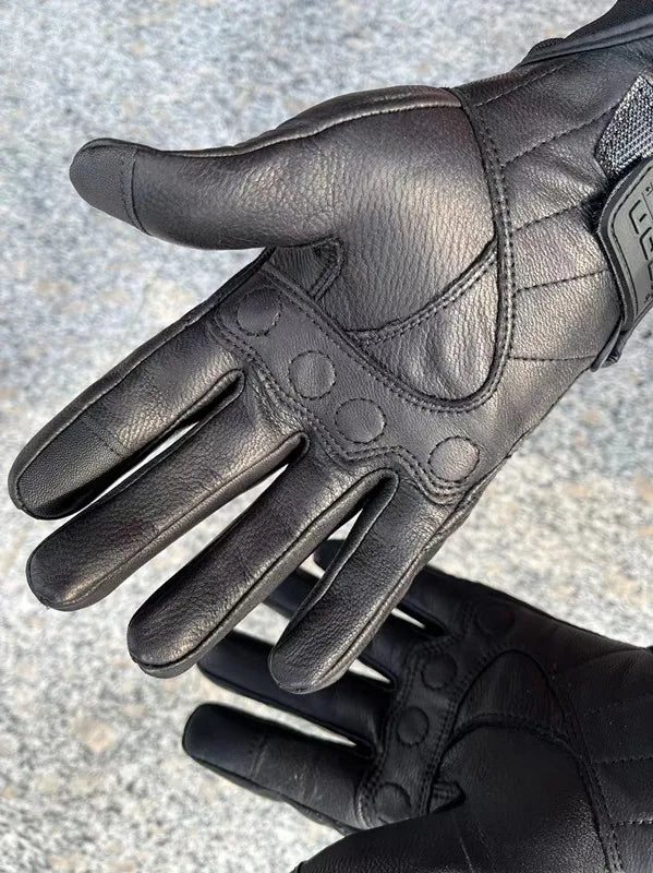 A close-up of black leather motorcycle riding gloves showing the palm and fingers.