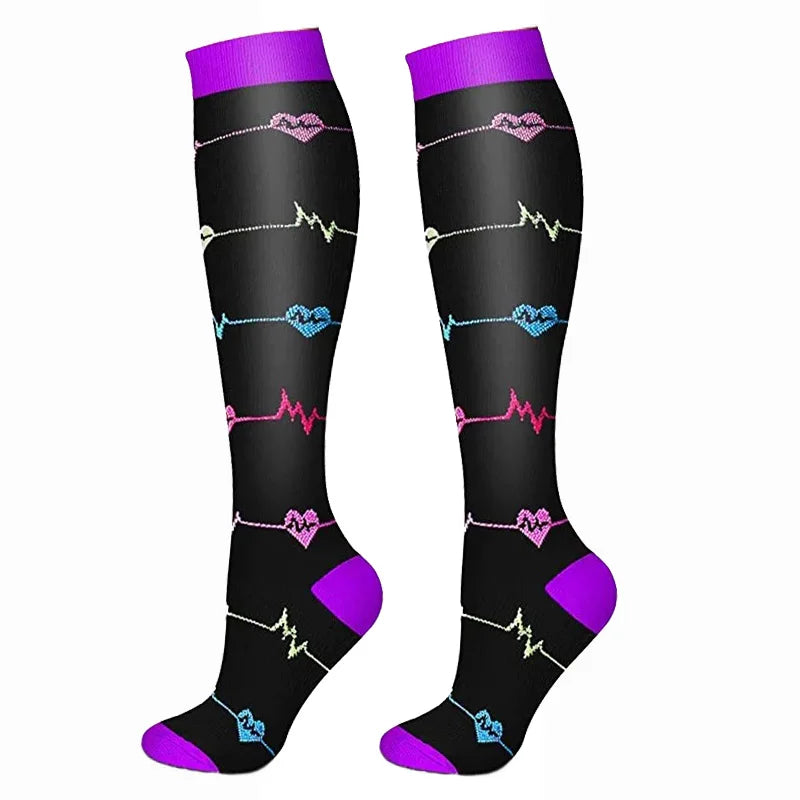 A pair of black compression elastic socks with purple cuffs and pink, blue, and yellow electrical heart rate line patterns.