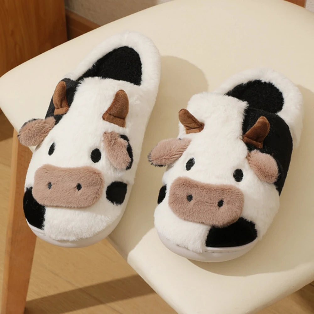 Pair of cartoon cow winter home slippers in white and black with brown accents