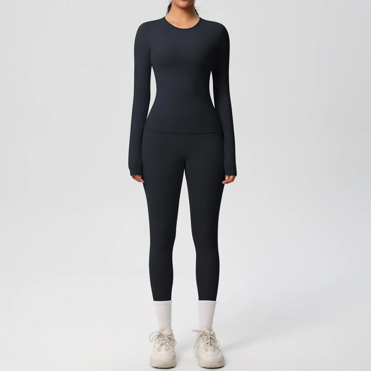 A woman wearing a navy blue long-sleeved performance yoga and gym set with white socks.