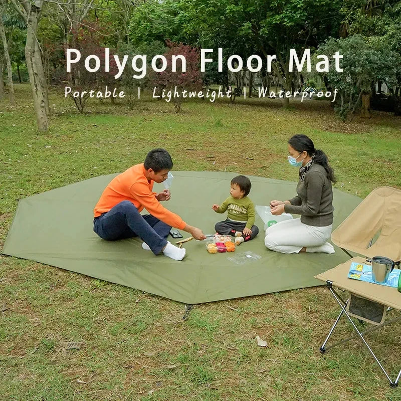 A family is using a green polygon floor mat for an outdoor picnic on the grass.