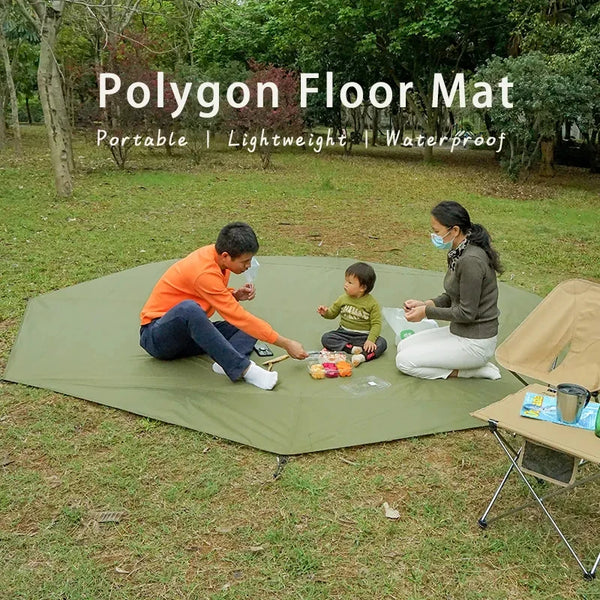 A family is using a green polygon floor mat for an outdoor picnic on the grass.