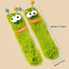 Pair of funny plush caterpillar floor socks in bright green with yellow and blue accents.