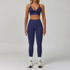 Eine Frau modelliert ein dunkelblaues, nahtloses Sport-Yoga-Set mit Crop-Top und Langhosen.