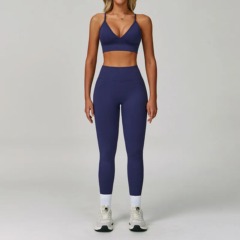 Eine Frau modelliert ein dunkelblaues, nahtloses Sport-Yoga-Set mit Crop-Top und Langhosen.