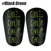 A pair of black shin guards with green text showing 'can' and a stick figure.