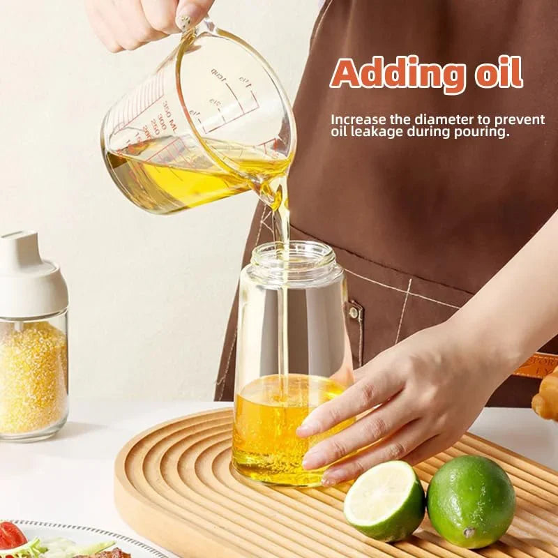 A hand pours oil from a glass measuring cup into a glass container for cooking.