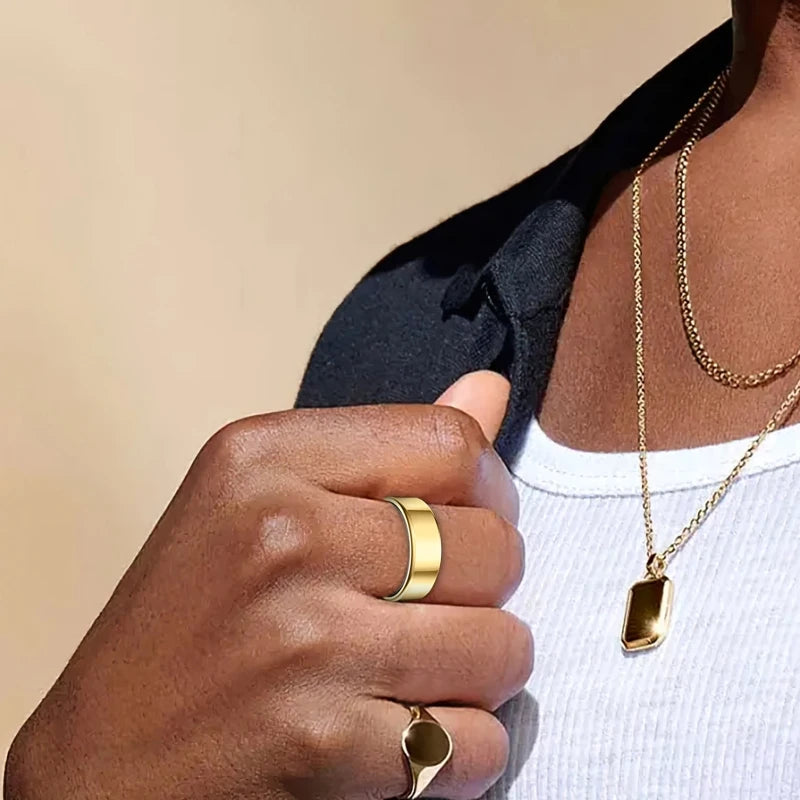 A hand wearing a gold ring and a gold necklace is visible against a dark shirt and white top.