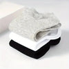 A stack of gray, white, and black comfort fit ankle socks is displayed on a white surface.