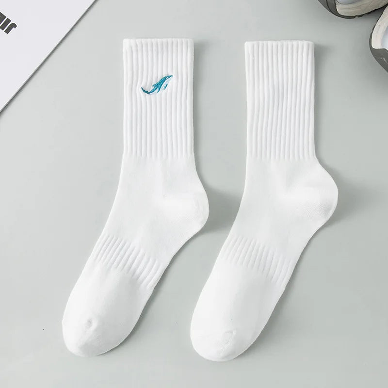 A pair of white men's athletic crew socks with a blue embroidered design on the foot.