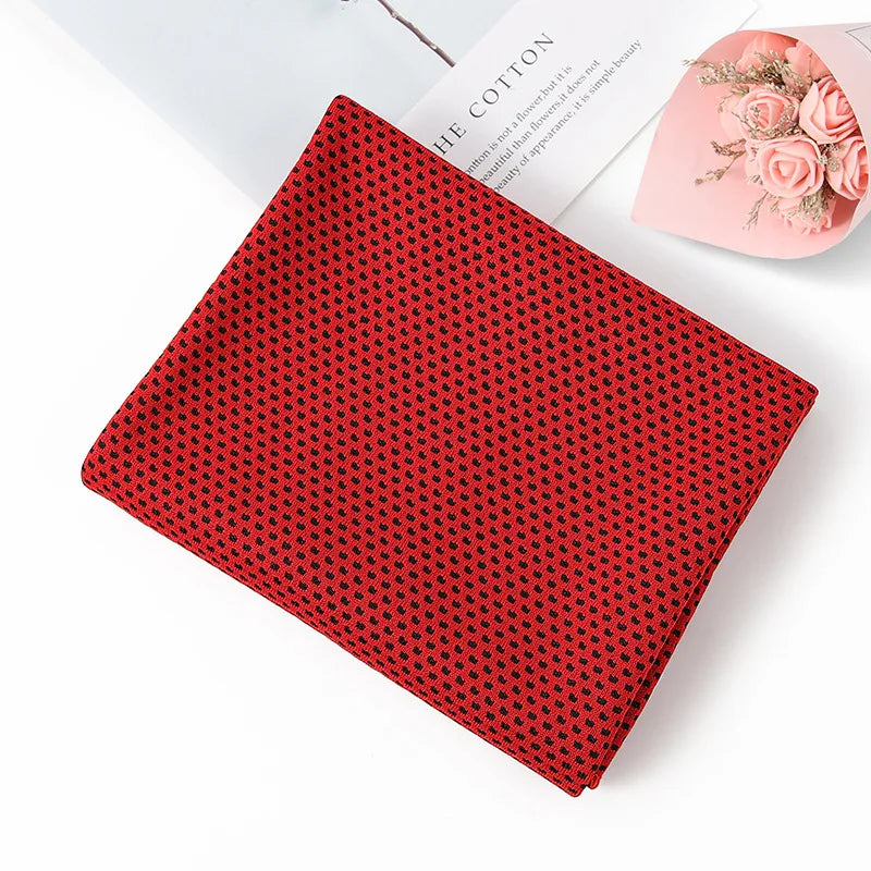 A red microfiber cooling towel with a black geometric pattern is shown on a white surface.