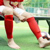 Person in red breathable football calf socks sitting on a green field.