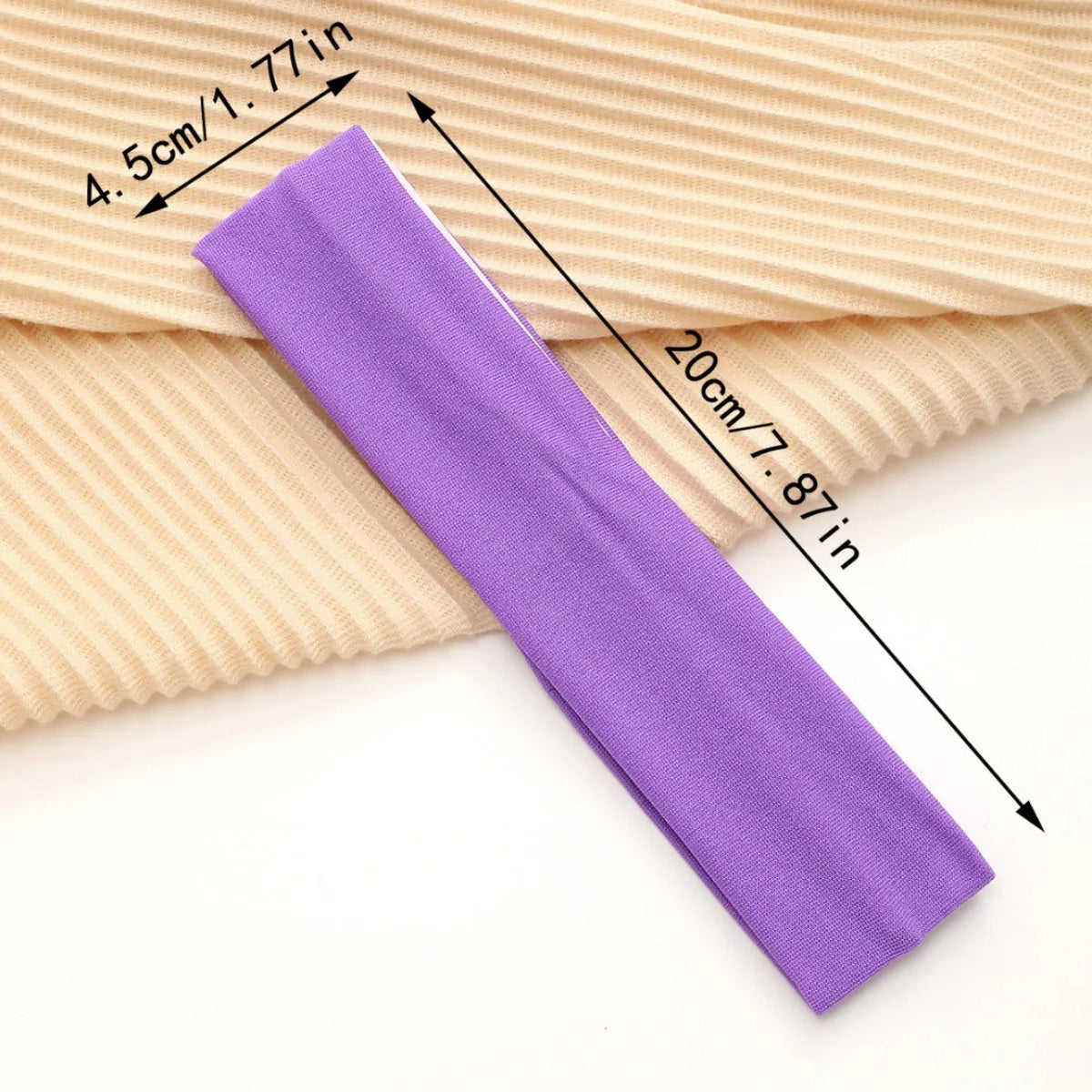 A purple stretchable cotton sweat absorbing headband is shown next to a beige ribbed fabric, illustrating its size.