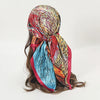 A colorful satin square scarf featuring abstract patterns in red, orange, blue, and gold, styled for hijab or hair.