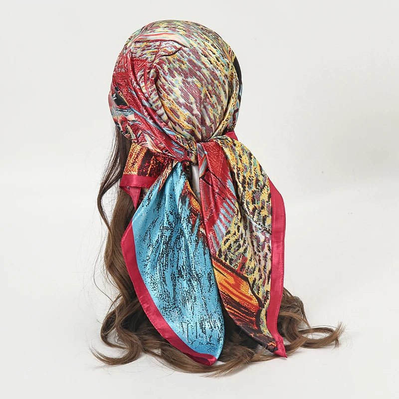 A colorful satin square scarf featuring abstract patterns in red, orange, blue, and gold, styled for hijab or hair.