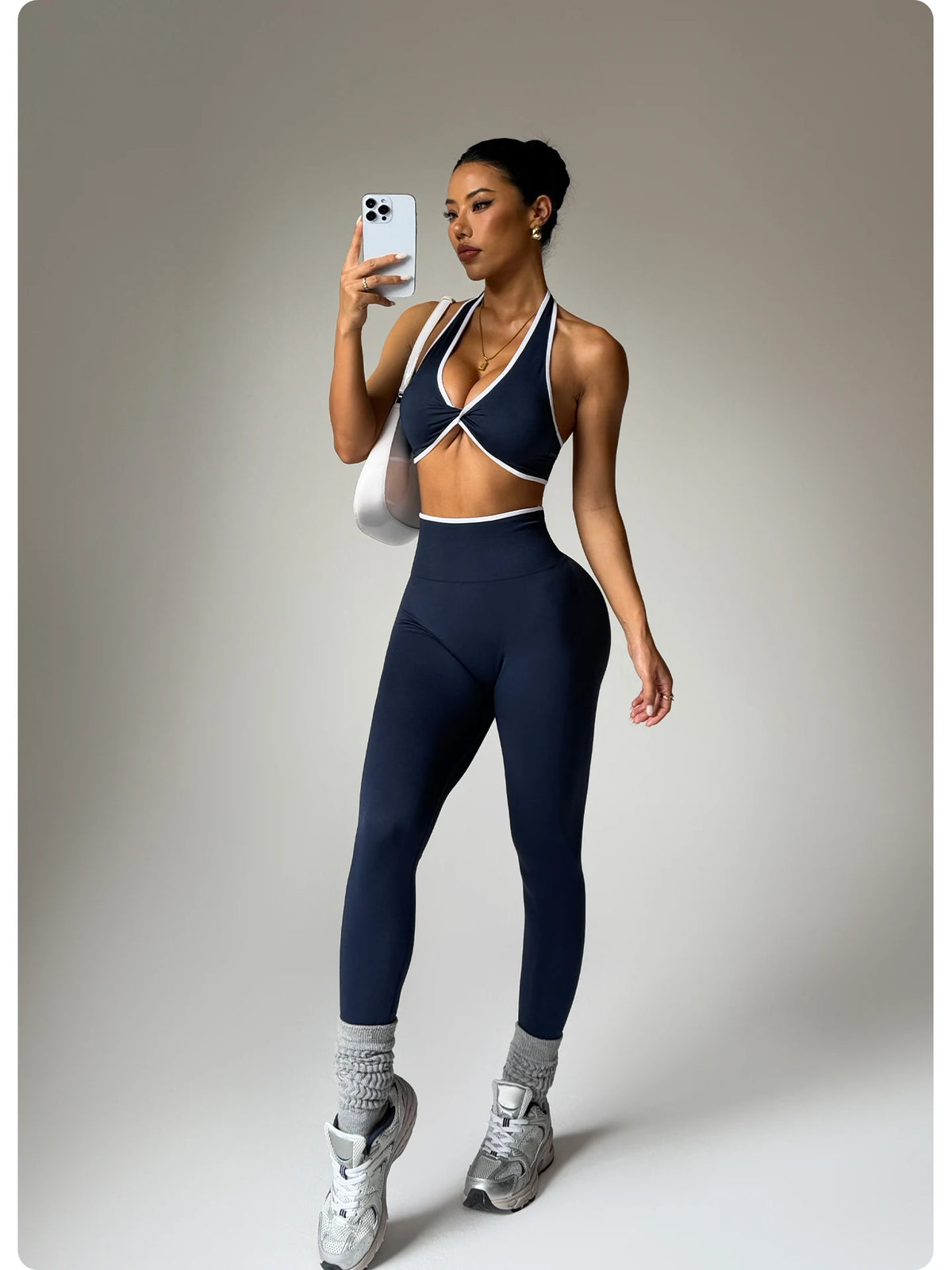 Eine Frau modelliert ein dunkelblaues, zweiteiliges Sport-BH mit Kontrastrand und Leggingset ohne Nähte.