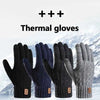A close-up of black and navy thermal gloves shown against a snowy mountain background.