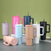 Collection de tasses isothermes en acier inoxydable de différentes couleurs avec paille, présentées sur une surface grise.