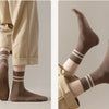 A pair of brown casual striped men's socks worn on a foot, shown in a close-up view.