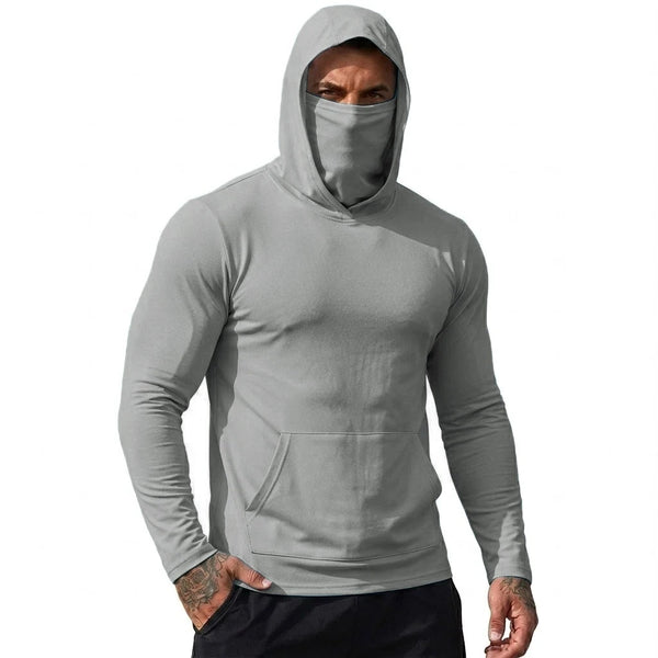 A man wearing a gray hooded sweatshirt with a face mask and black pants.