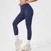 Person in dark navy seamless high-waist yoga leggings and light colored athletic shoes.