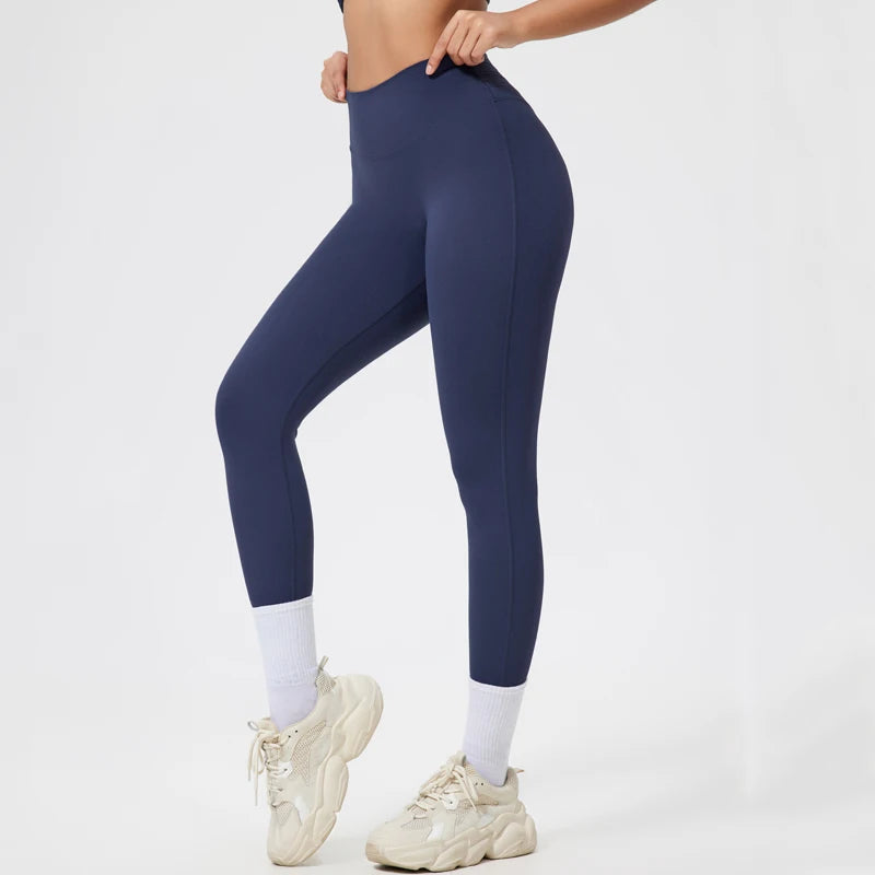 Person in dark navy seamless high-waist yoga leggings and light colored athletic shoes.