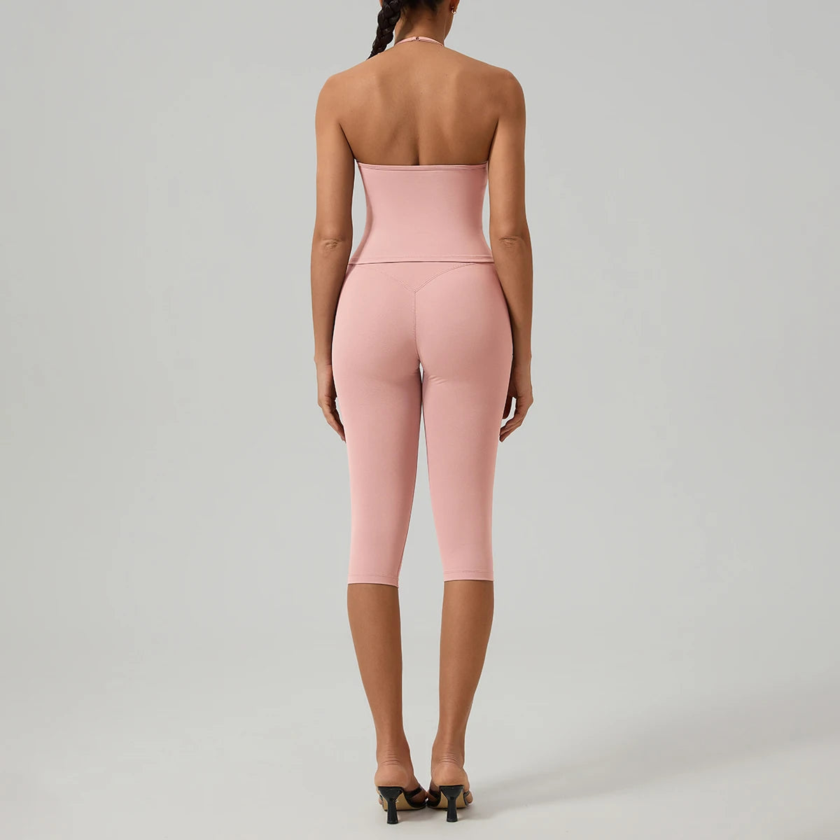 Eine Frau trägt ein pinkes zwei-teiliges Yoga-Activewear-Set mit Crop-Top und Leggings.