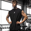Muskulöser Mann in einem schwarzen Fitness-Tanktop steht in einem Fitnessstudio.