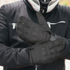 A person wearing black motorcycle riding full finger gloves and a black jacket.