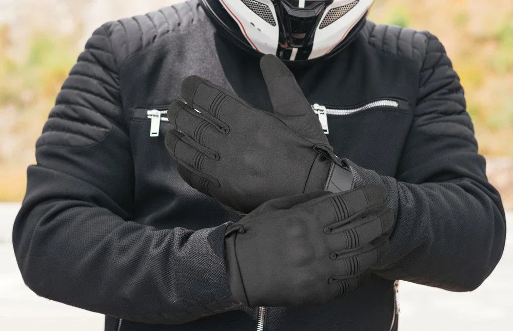 A person wearing black motorcycle riding full finger gloves and a black jacket.