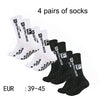 Four pairs of black and white men's athletic soccer socks with non-slip grip