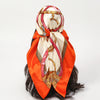 An elegant satin square scarf featuring a pink and gold ornate design tied around dark hair.