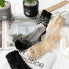 A collection of sheer invisible lace socks in black and beige are displayed on a white surface.