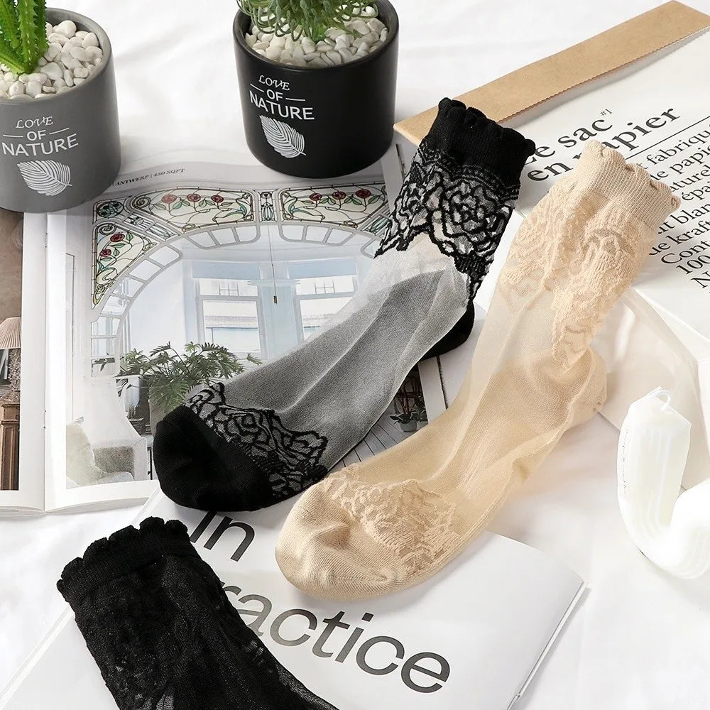 A collection of sheer invisible lace socks in black and beige are displayed on a white surface.