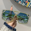A hand holds a pair of green geometric rhinestone fashion sunglasses against a white background.