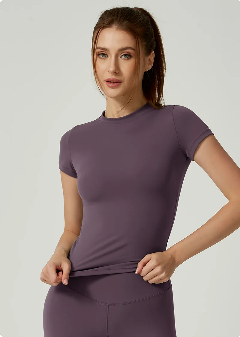 Una mujer modela un conjunto deportivo de yoga color malva, de cintura alta, en un estudio.