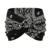 Black fabric headband featuring white paisley embroidery and a twisted design