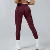 A person wearing maroon high-waist yoga leggings and white socks, standing in a full-length shot.
