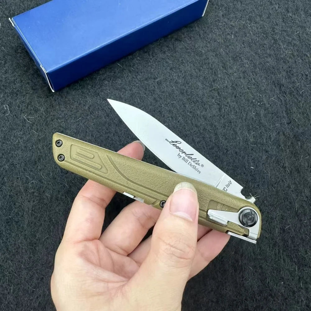 A hand holds a light olive green precision folding pocket knife with a silver blade and a blue box in the background.