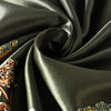 Tela de satén verde oliva oscuro con estampado paisley marrón y dorado, drapeada dramáticamente.