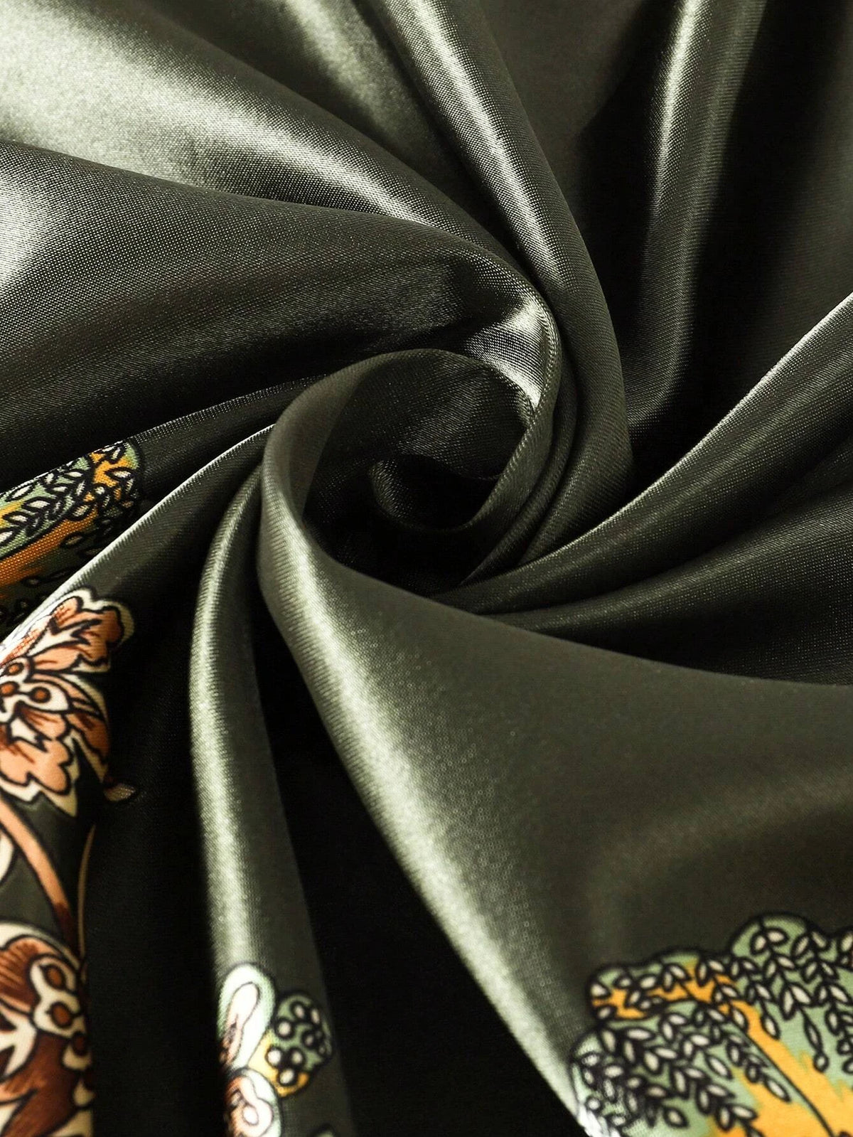 Tela de satén verde oliva oscuro con estampado paisley marrón y dorado, drapeada dramáticamente.