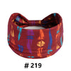 A maroon patterned fabric headband with a bow, featuring abstract designs in orange, blue, and purple.