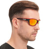 A man wearing orange-tinted sunglasses with black frames against a white background.