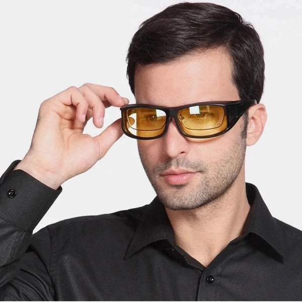 Un hombre con gafas de sol tintadas en ámbar y visión nocturna conduciendo, mirando directamente a la cámara.