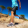 A person running outdoors wearing black compression thigh sleeves and a bright blue shirt.